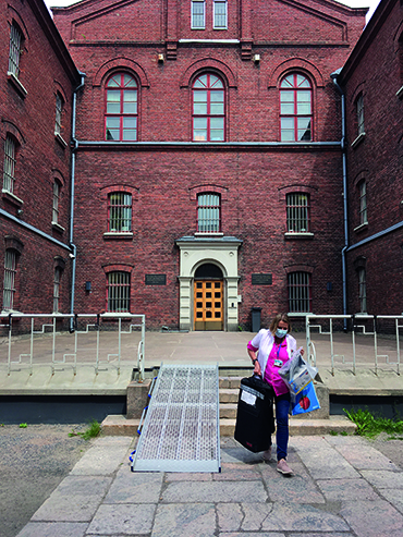 Hoitaja kantaa tavaroita vankilan sisäpihalla.