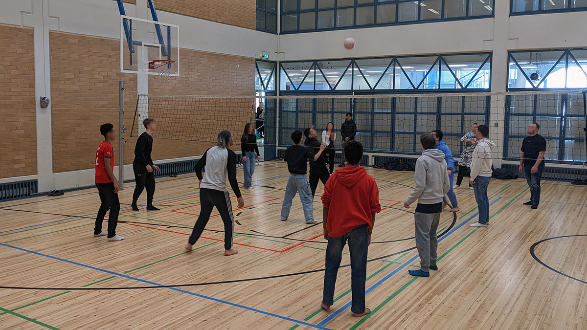 Nuoria pelaa lentopalloa liikuntasalissa.