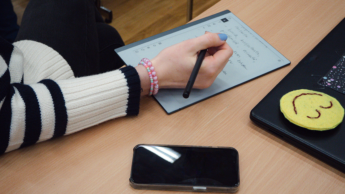 Ihminen kirjoittelee pöydän ääressä.