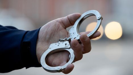 Kädiraudat henkilön (poliisin) kädessä