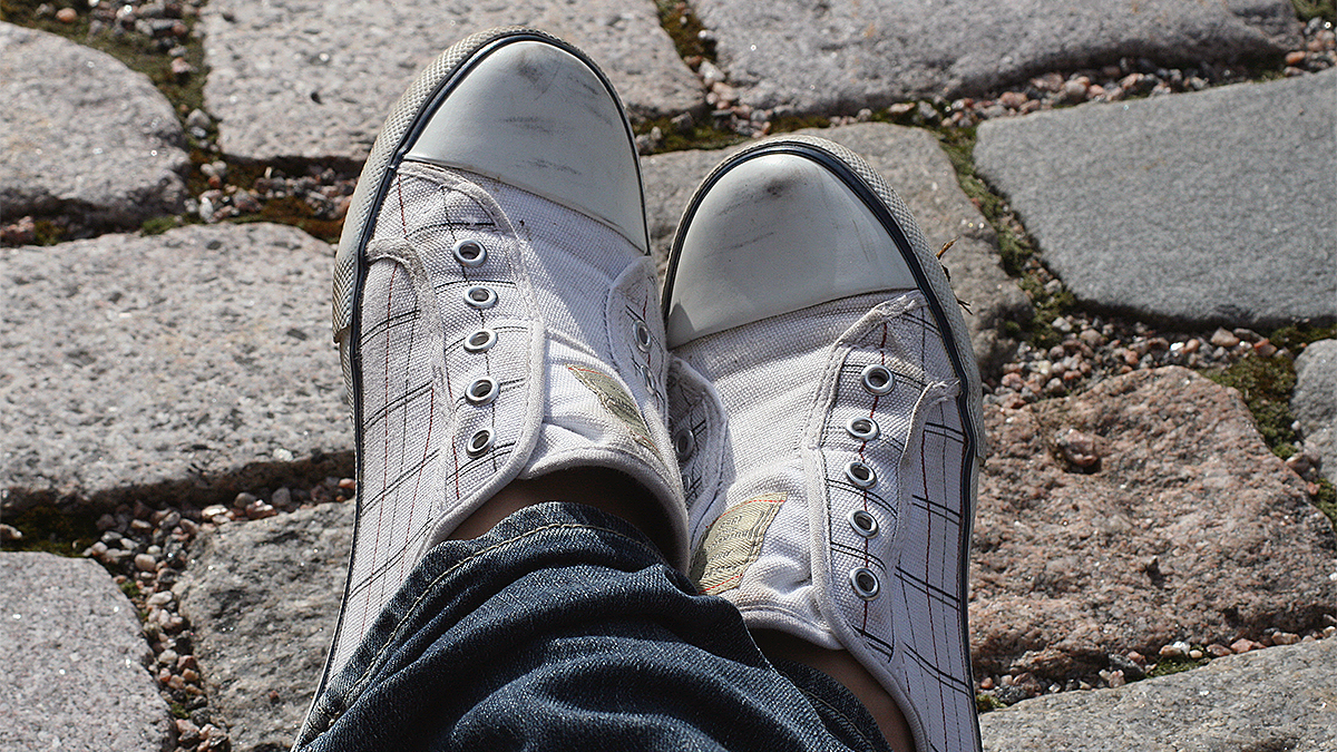 Närbild av en ung persons fötter med skor.