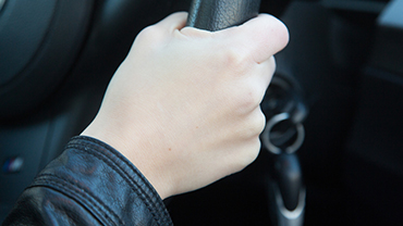 Nahkatakkisen miehen käsi pitää kiinni ratista.