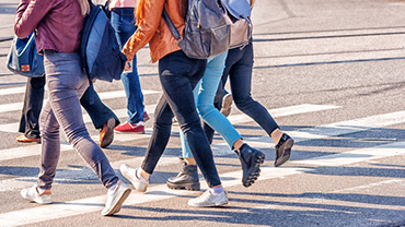 Suojatietä ylittävän nuorisoryhmän jalat.