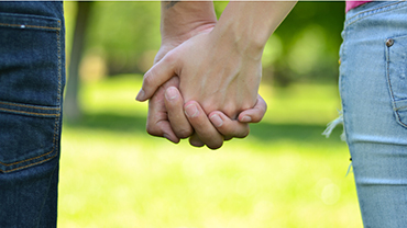 Lähikuva pariskunnan käsistä puistossa.