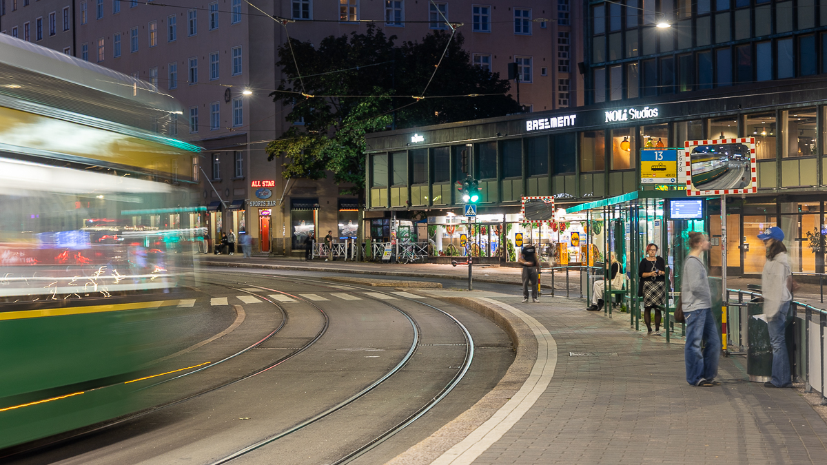 Iltakuva, ihmisiä Sörnaisten raitiovaunupysäkillä.