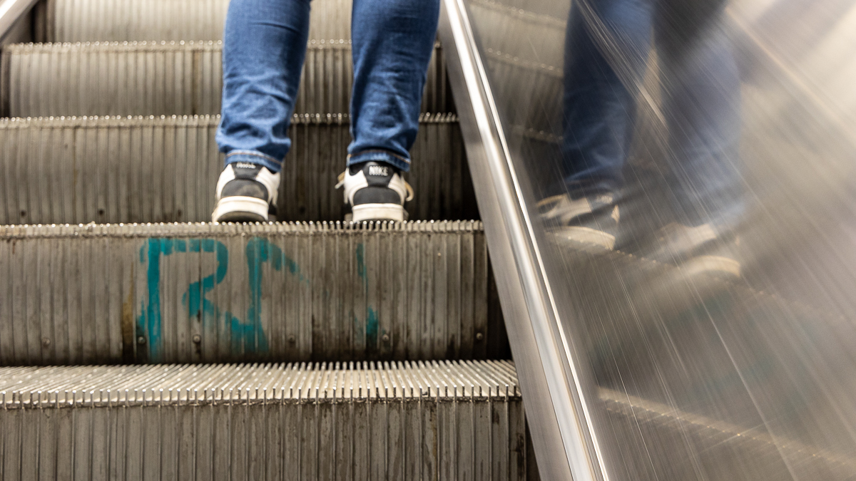 Ihmisen jalat graffiteilla töhrityissä liukuportaissa.