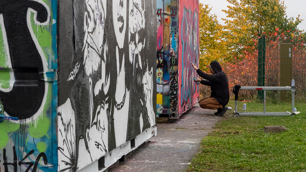 Young person paints graffiti.