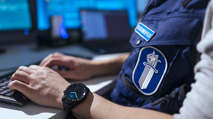 Virkapukuisen poliisin kädet näppäimistöllä.